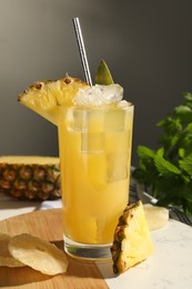 Photo of Tasty pineapple cocktail with ice cubes and delicious fruit on table