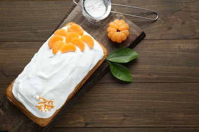 Delicious homemade yogurt cake with tangerines and cream on wooden table, flat lay. Space for text
