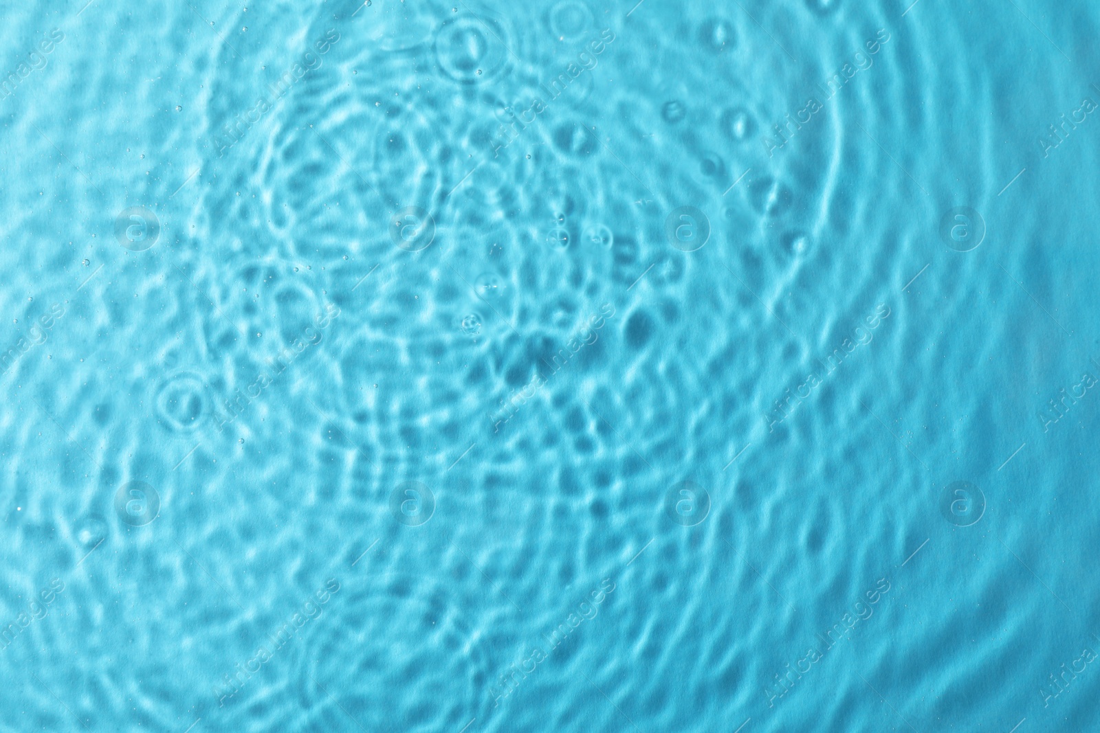 Photo of Clear water with rippled surface on light blue background, top view