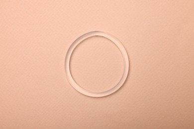 Photo of Diaphragm vaginal contraceptive ring on beige background, top view