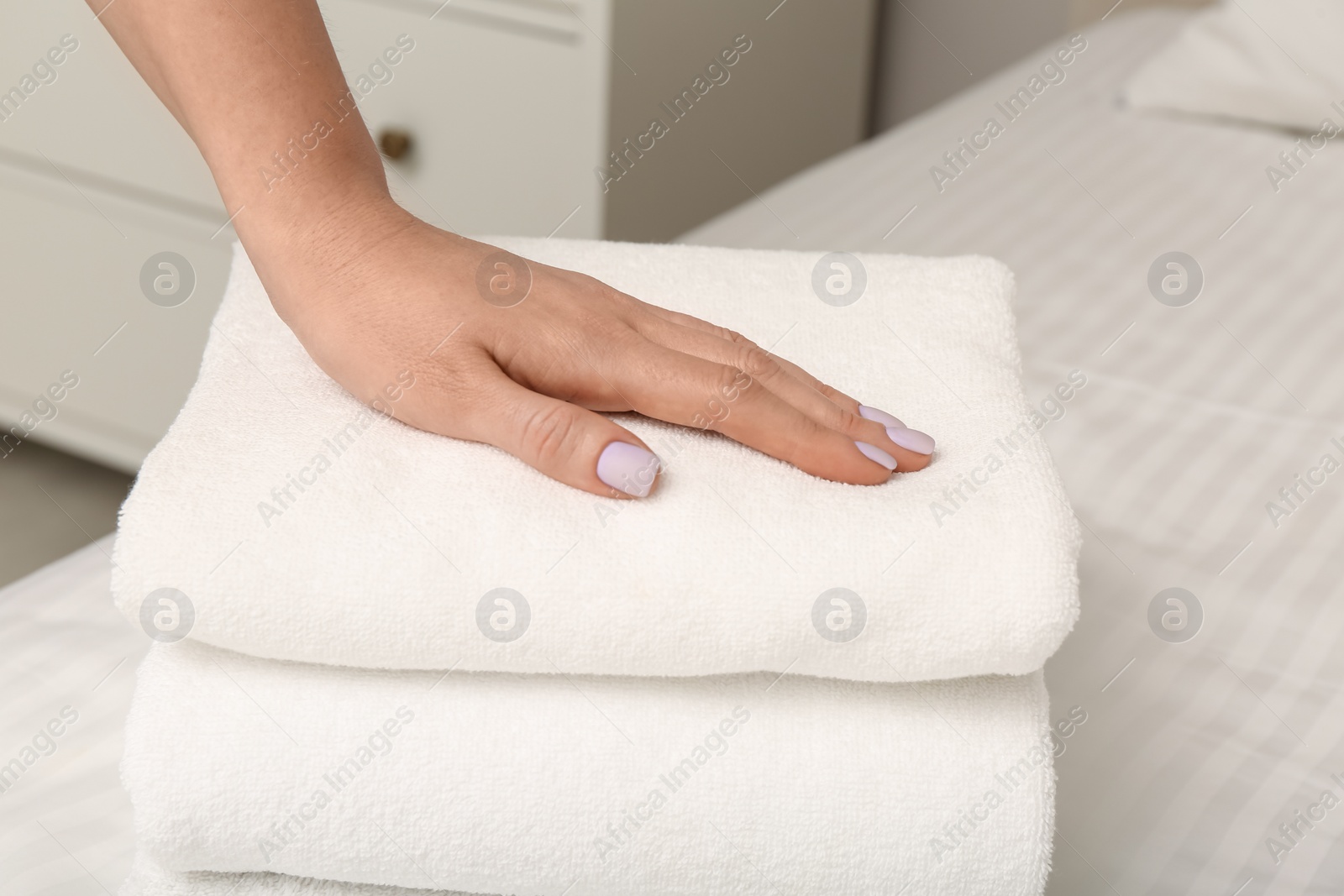 Photo of Woman touching soft towel on bed, closeup