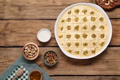 Photo of Making delicious baklava. Raw dough with ingredients on wooden table, flat lay
