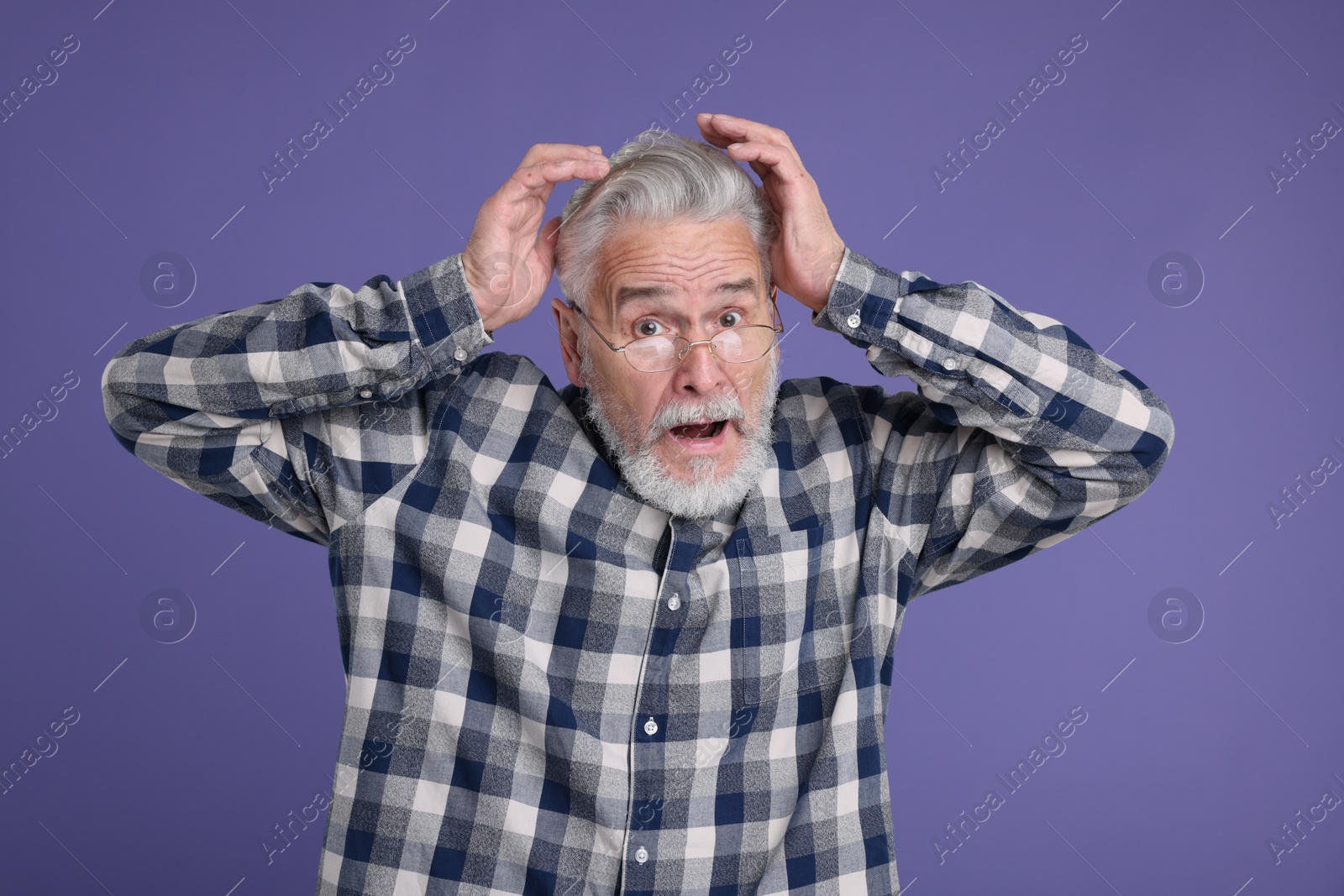 Photo of Portrait of surprised senior man on violet background