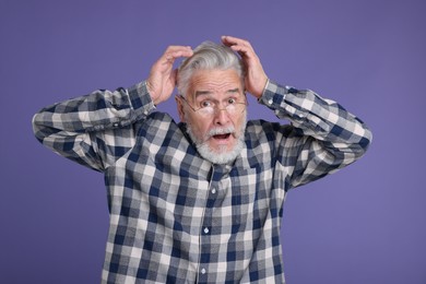 Portrait of surprised senior man on violet background
