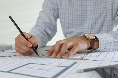 Architect working with construction drawings indoors, closeup