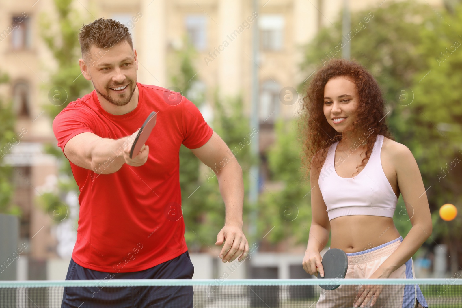 Photo of Friends playing ping pong outdoors on summer day