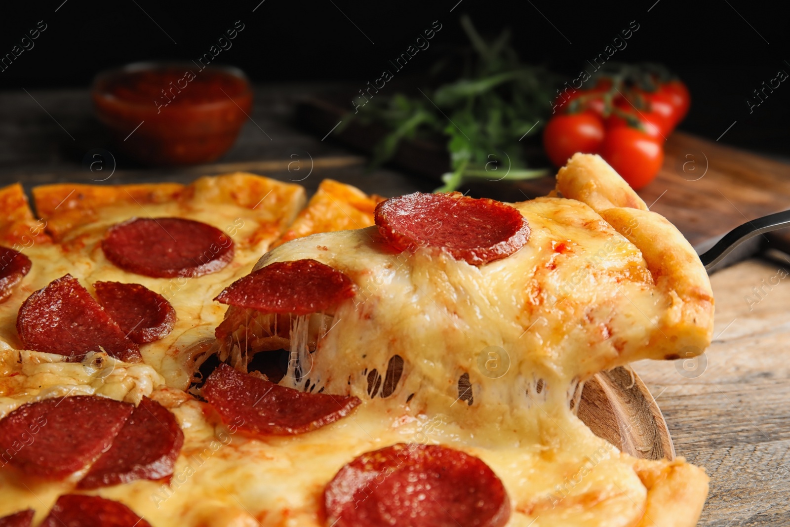 Photo of Taking slice of tasty pepperoni pizza on wooden table, closeup