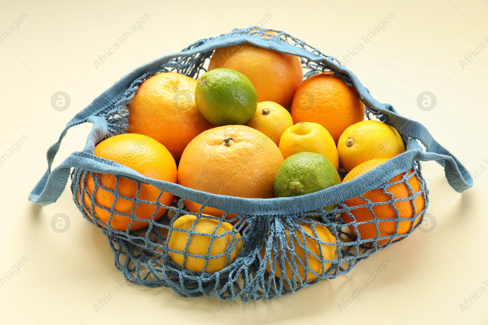 Photo of String bag with different fruits on beige background