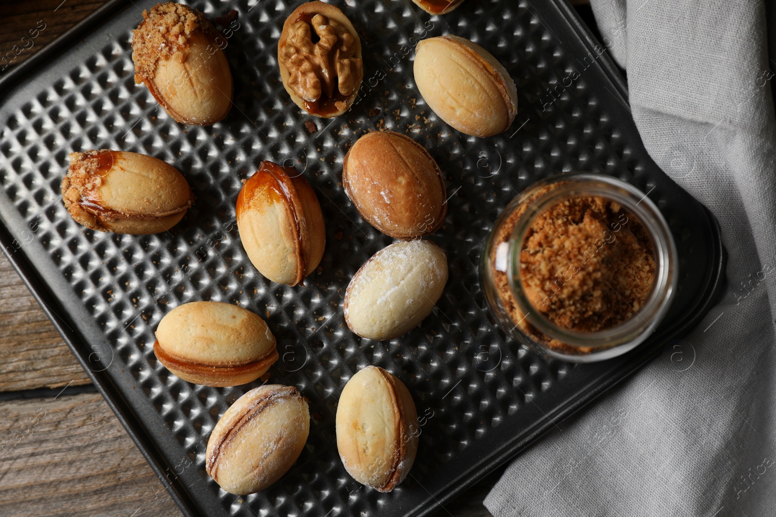 Photo of Freshly baked homemade walnut shaped cookies and topping on wooden table, top view