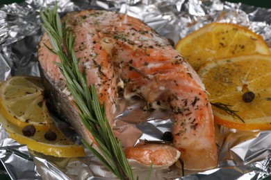 Photo of Tasty salmon with citrus fruits and rosemary baked in foil, closeup