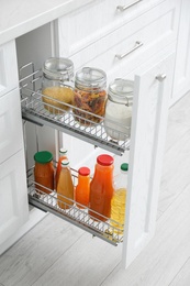 Photo of Open drawer with jars of food and juice bottles in kitchen