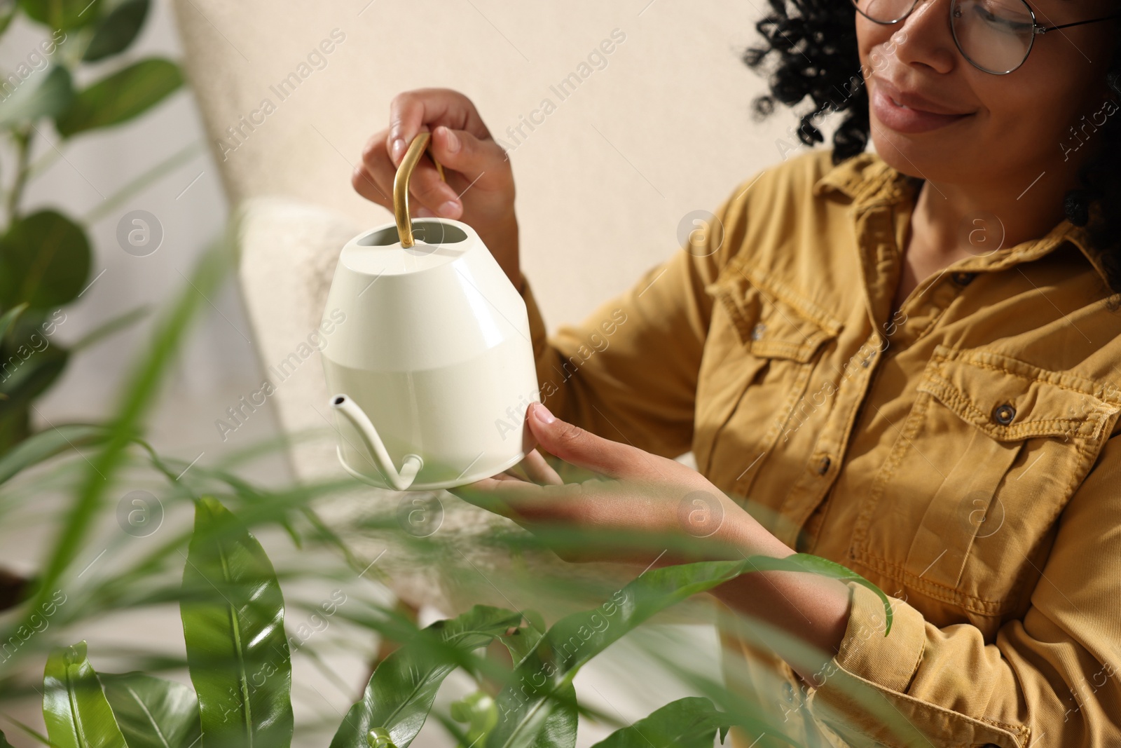 Photo of Woman watering beautiful houseplants indoors, closeup view