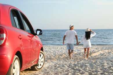 Photo of Couple walking on sandy beach, back view. Summer trip