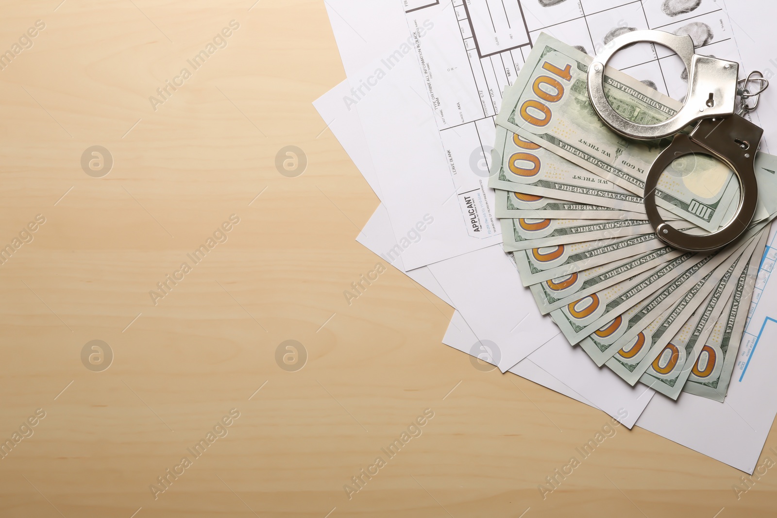 Photo of Money, handcuffs and fingerprint record sheets on wooden background, top view with space for text. Criminal investigation