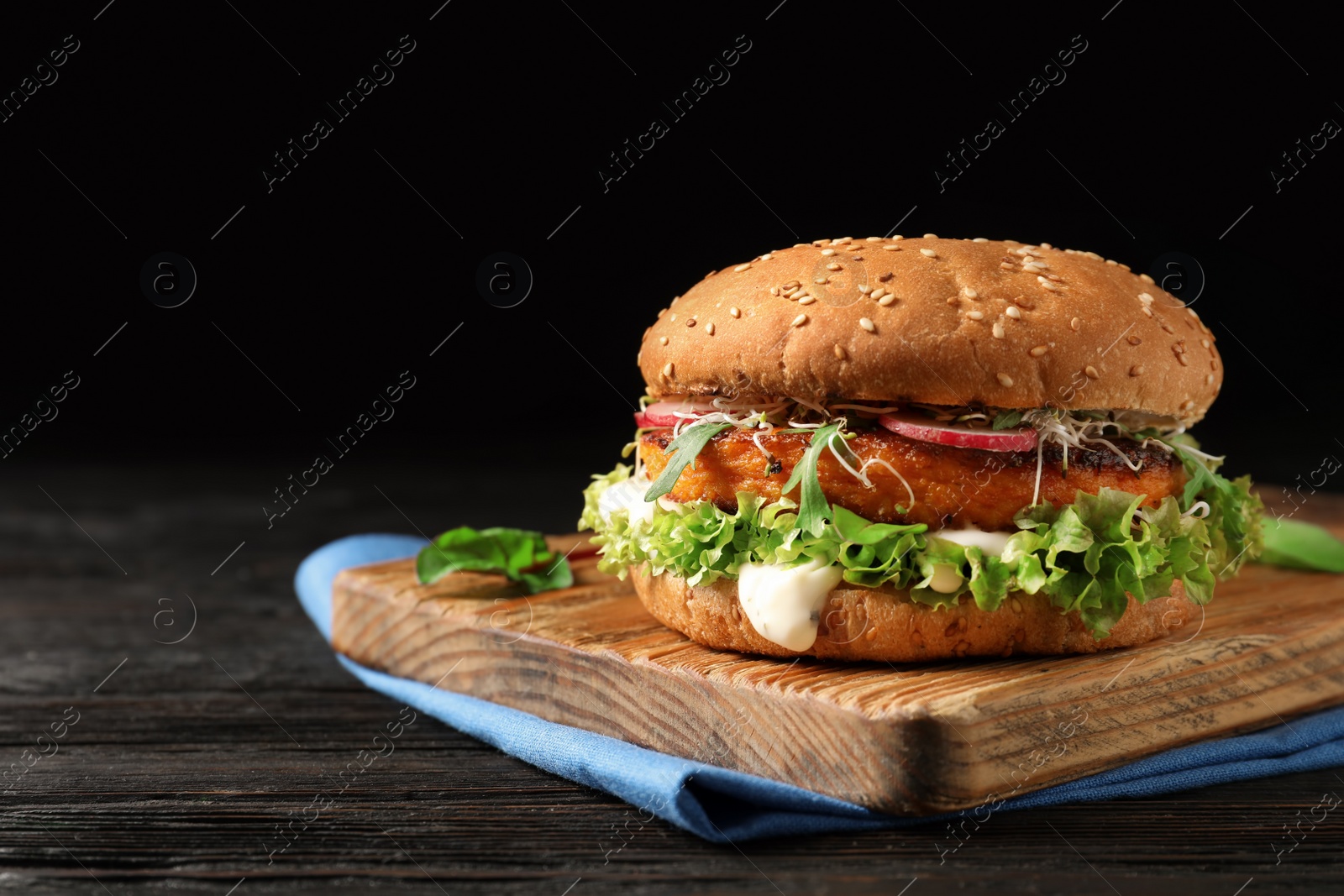 Photo of Board with tasty vegetarian burger on wooden table