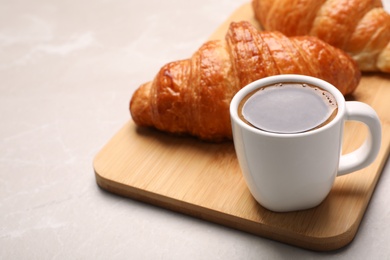 Photo of Wooden board with cup of coffee and croissants on table