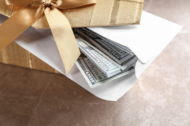 Gift box with dollar bills on brown marble table, closeup