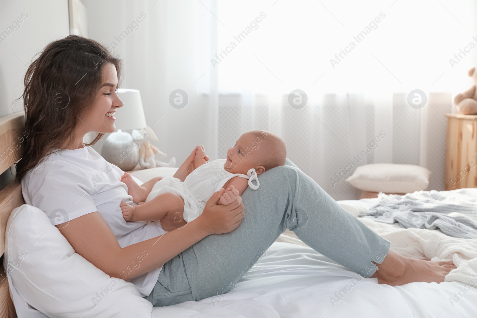 Photo of Happy young mother with her cute baby on bed at home