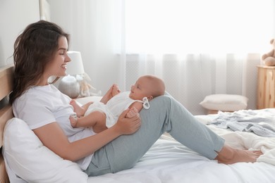 Happy young mother with her cute baby on bed at home