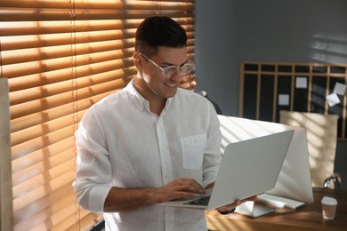 Photo of Freelancer working on laptop near window indoors