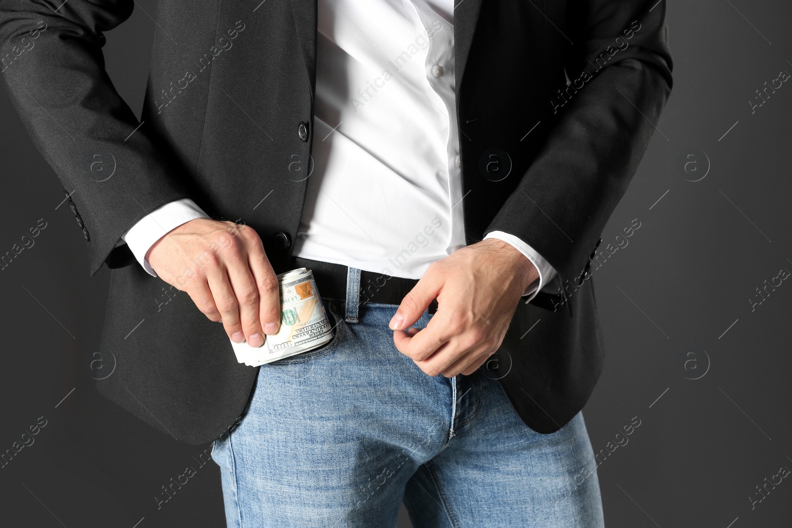 Photo of Man putting bribe money into pocket on black background, closeup