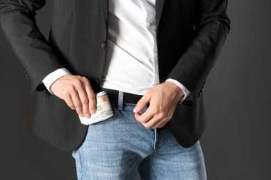 Man putting bribe money into pocket on black background, closeup