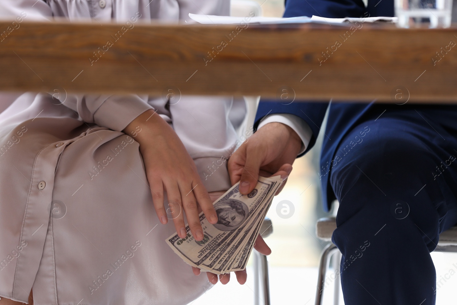 Photo of Man giving bribe money under table indoors, closeup
