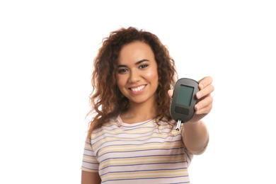 Photo of Young African-American woman holding glucometer on white background. Diabetes control