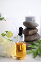 Photo of Bottle with essential oil on white marble table. Spa product