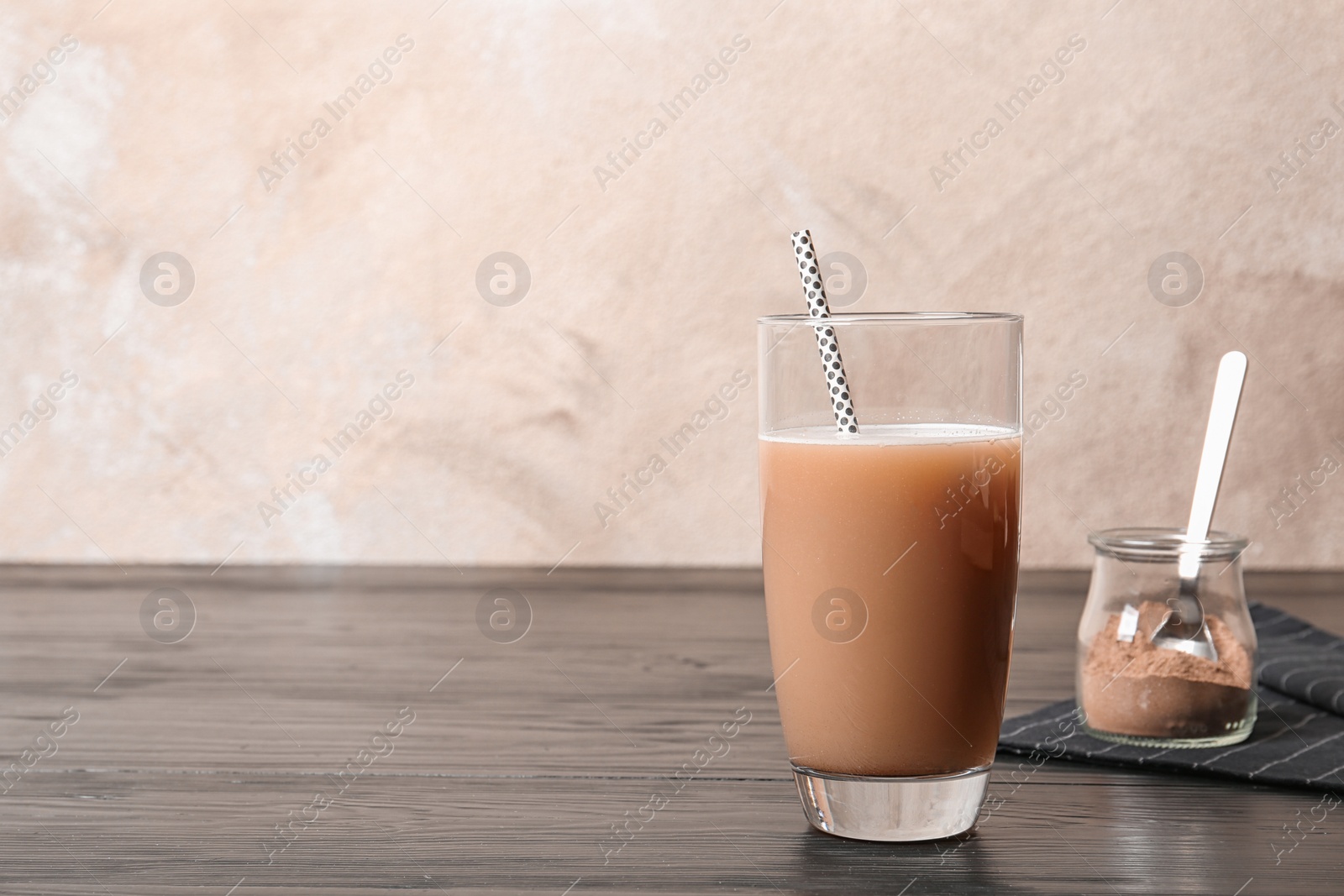 Photo of Glass of chocolate protein shake on wooden table. Space for text