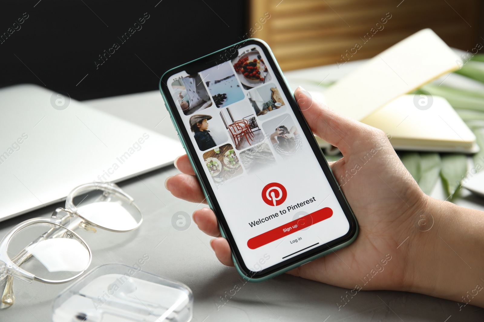 Photo of MYKOLAIV, UKRAINE - JULY 9, 2020: Woman holding Iphone 11 with Pinterest app on screen at table, closeup