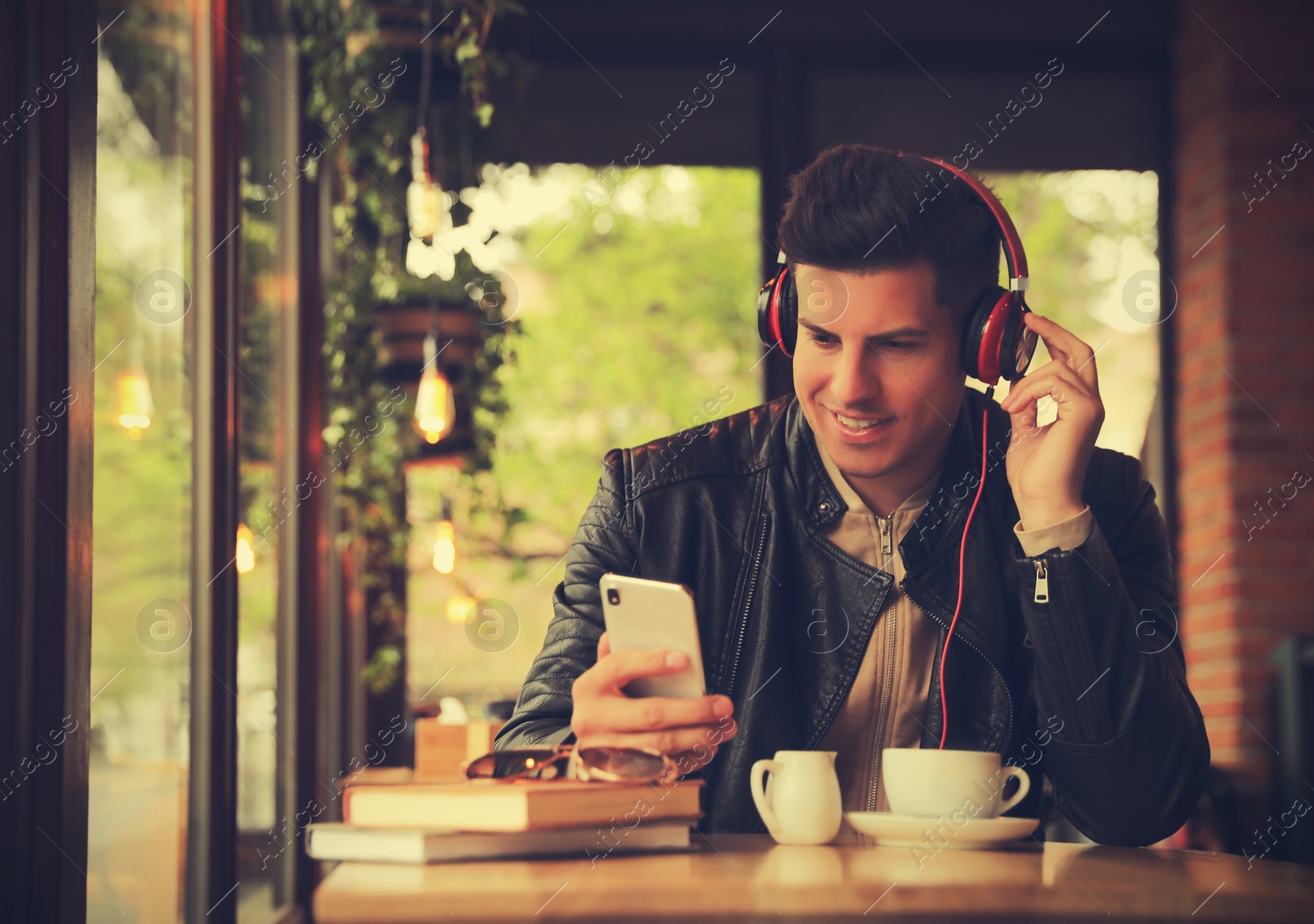 Photo of Man with smartphone listening to audiobook at table in cafe