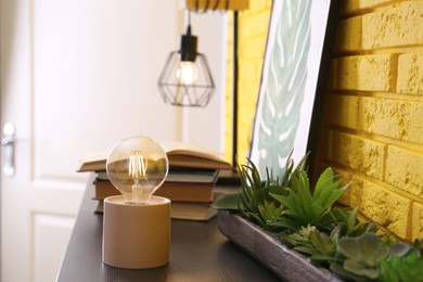 Photo of Modern night lamp, houseplants and decor on table in room