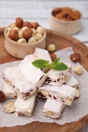 Pieces of delicious nougat and nuts on wooden board, closeup