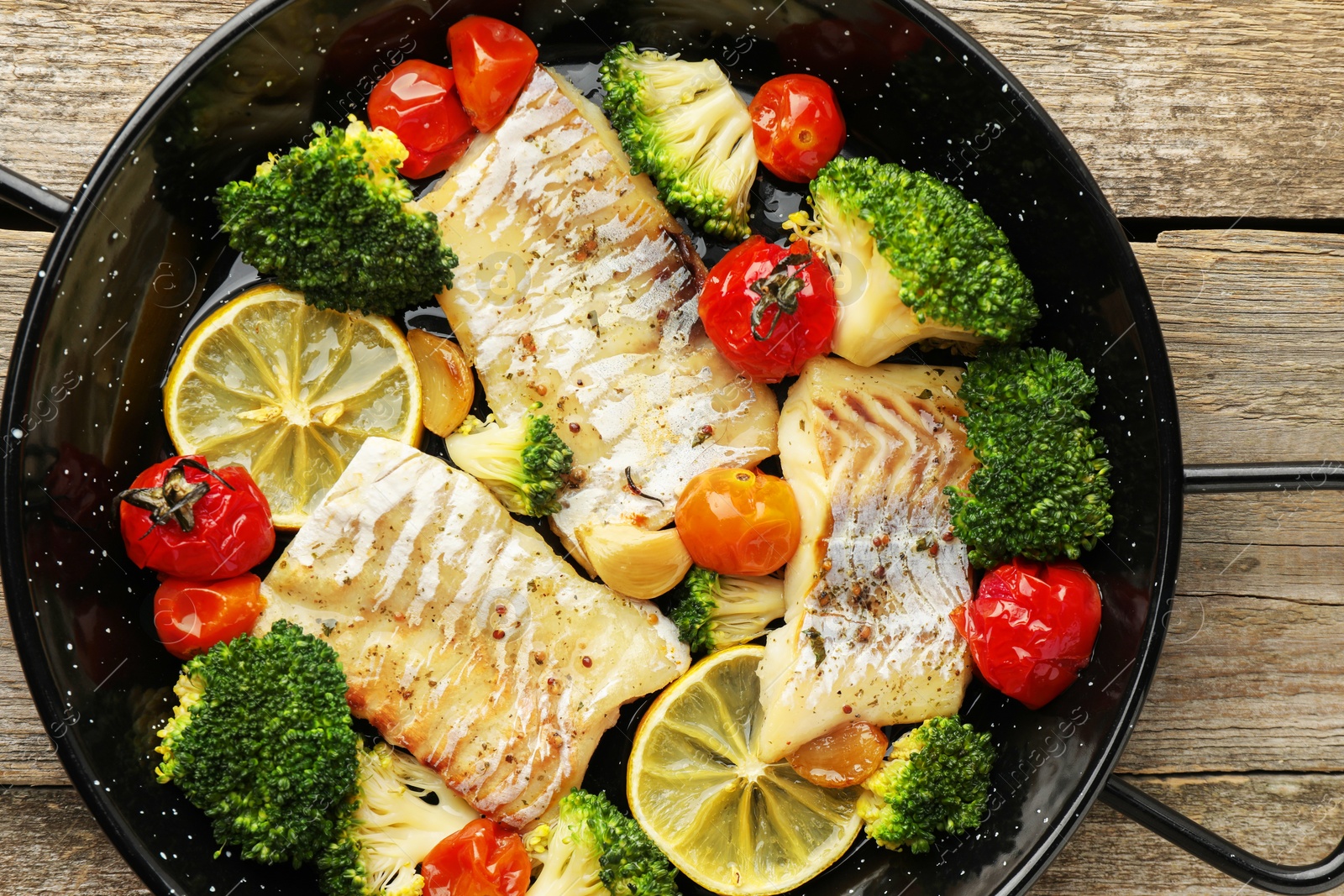 Photo of Tasty cod cooked with vegetables in frying pan on wooden table, top view