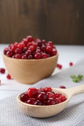 Photo of Spoon with fresh ripe cranberries on table, closeup