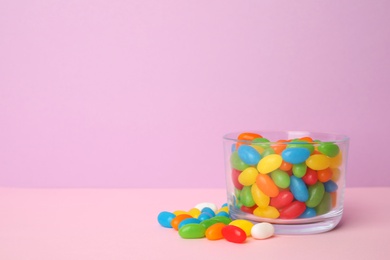 Photo of Glass of delicious jelly beans on color background. Space for text
