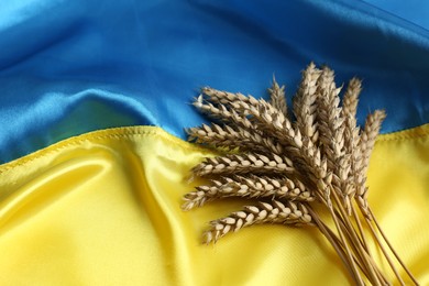 Photo of Ears of wheat on Ukrainian national flag, space for text
