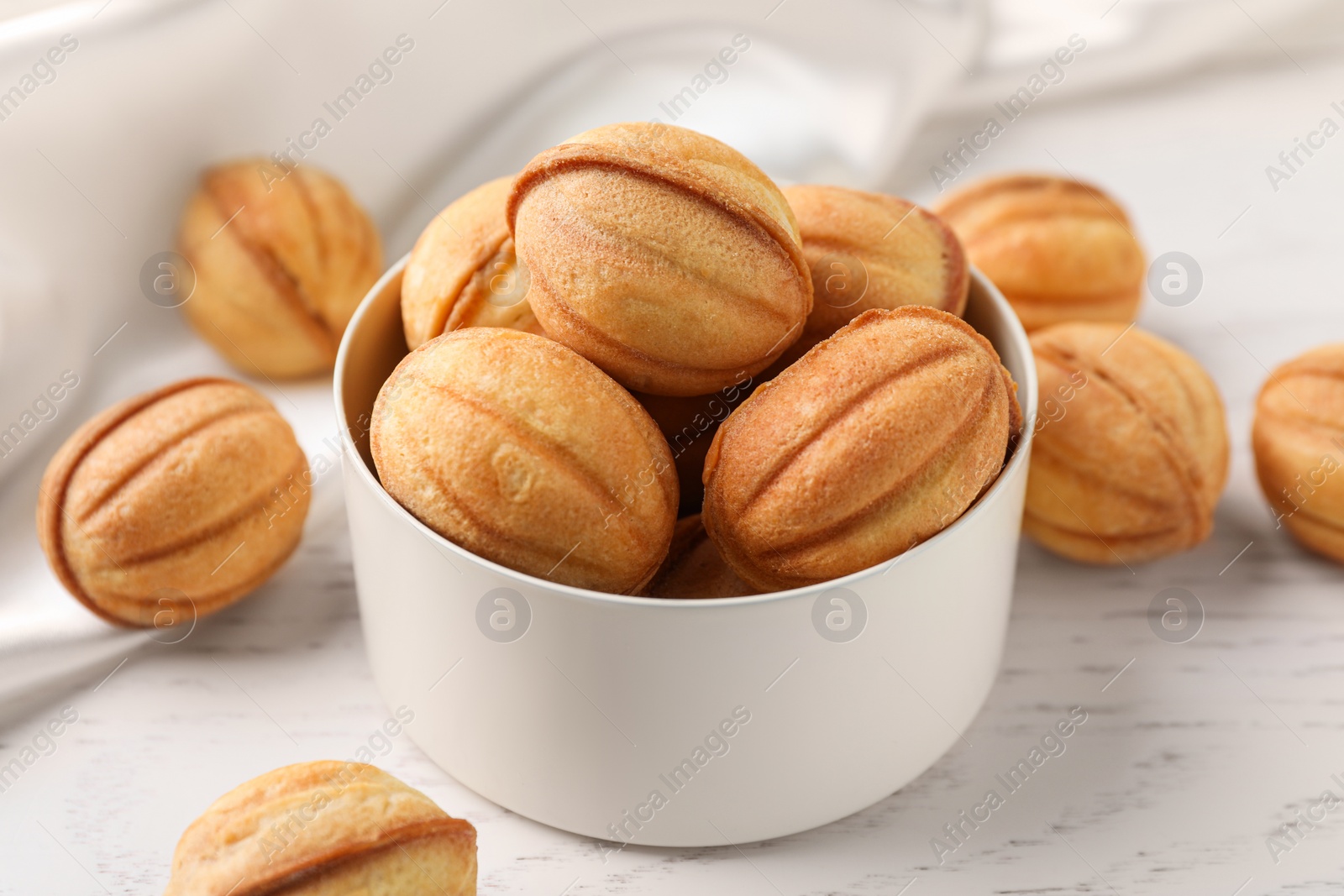 Photo of Delicious nut shaped cookies on white wooden table, closeup