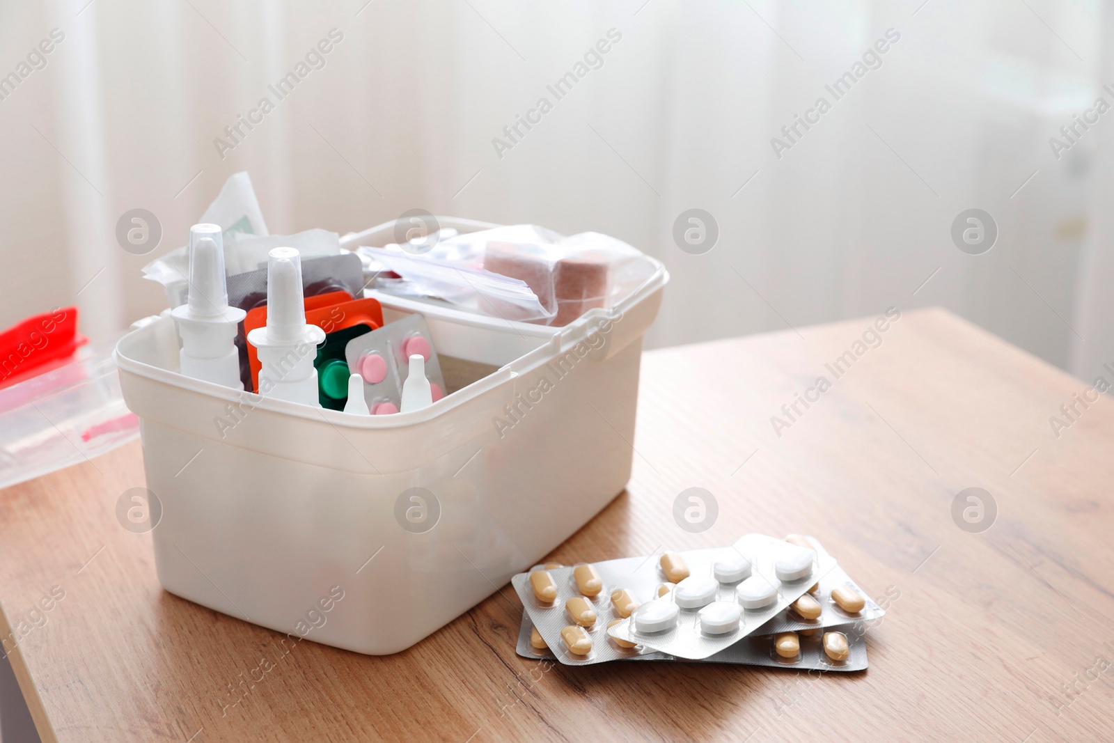 Photo of First aid kit and medicaments on wooden table indoors, closeup. Space for text