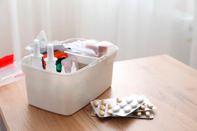 Photo of First aid kit and medicaments on wooden table indoors, closeup. Space for text