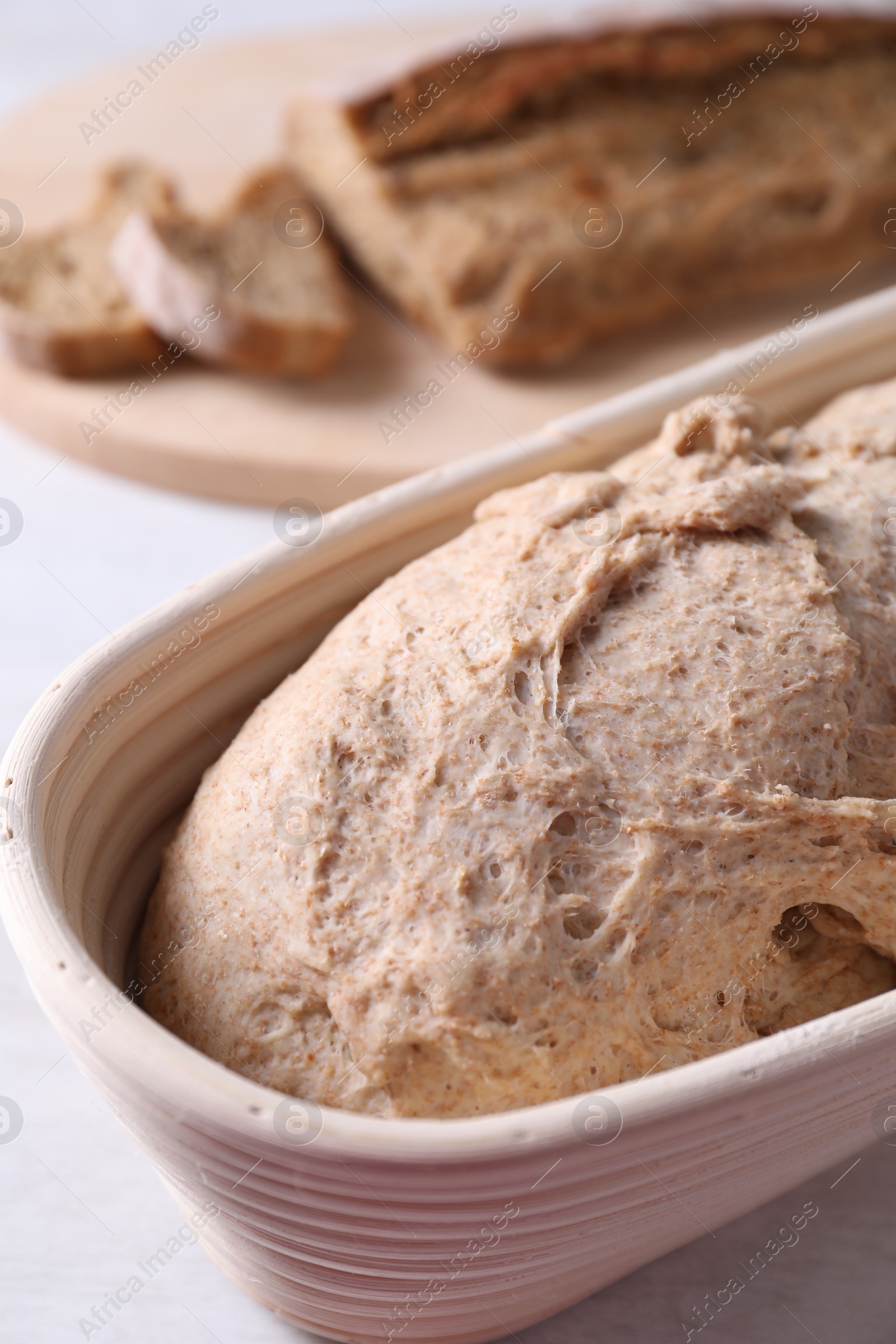 Photo of Fresh sourdough in proofing basket on table, closeup