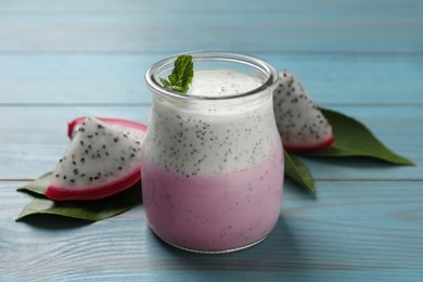 Photo of Tasty pitahaya smoothie, fruit and fresh mint on light blue wooden table