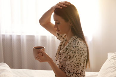 Photo of Young woman with drink on bed at home. Lazy morning