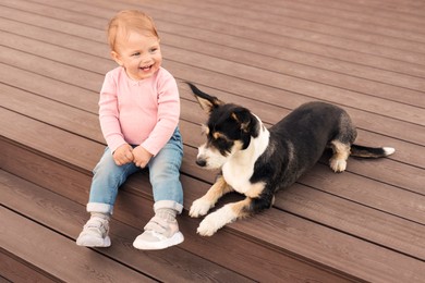 Photo of Adorable baby and furry little dog on wooden porch
