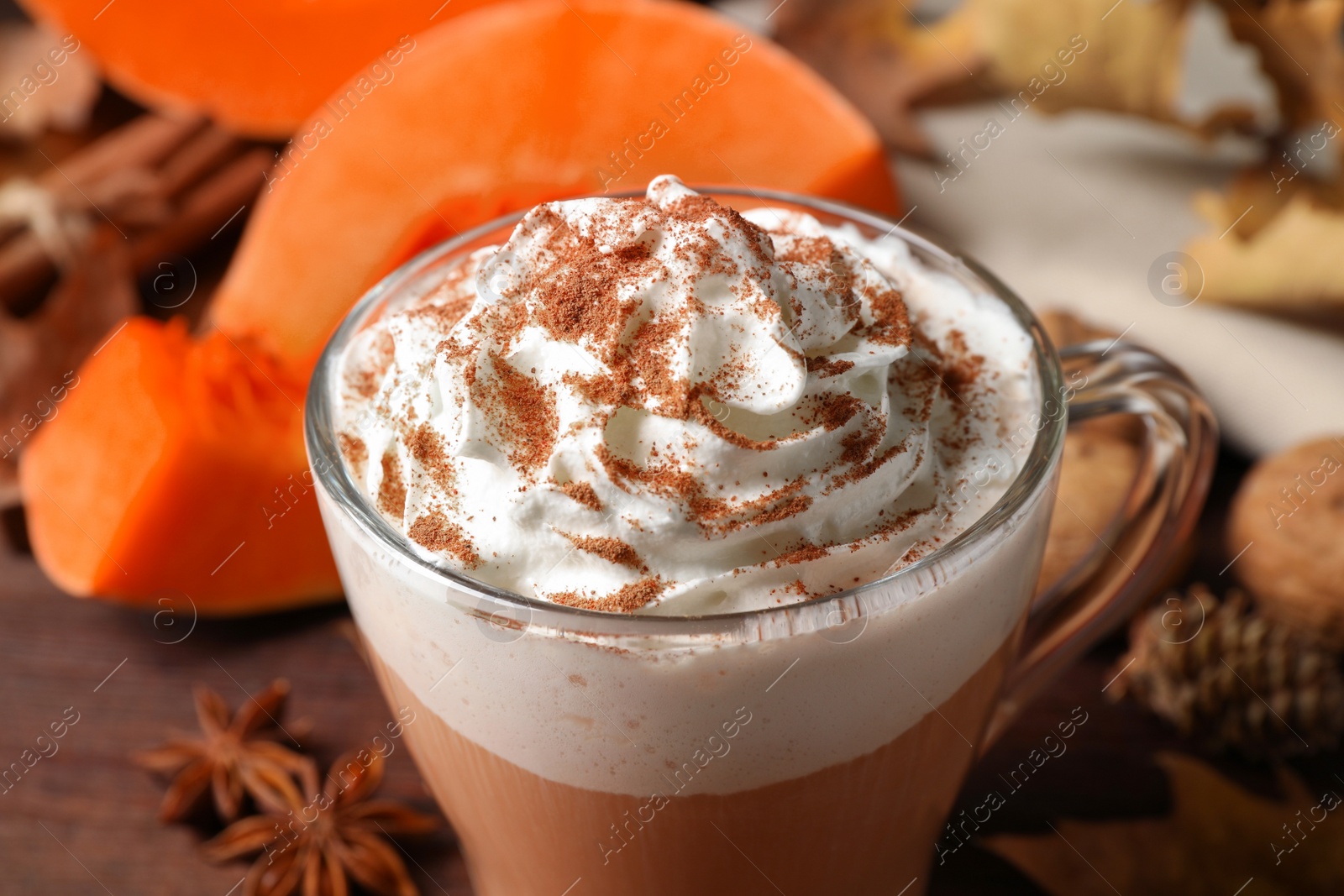 Photo of Delicious pumpkin latte with whipped cream on table, closeup