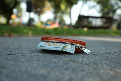 Photo of Brown leather purse on pavement outdoors. Lost and found