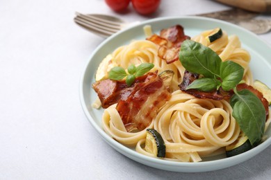 Photo of Tasty pasta with bacon and basil on light grey table, space for text