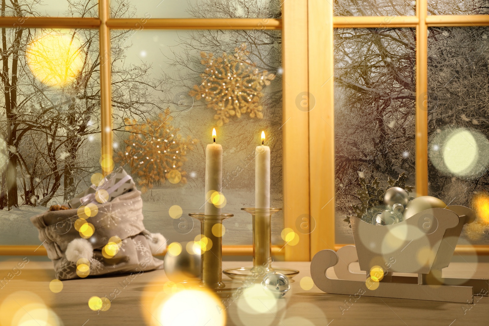 Image of Burning candles, bag with gift boxes and festive decor on window sill indoors. Christmas eve