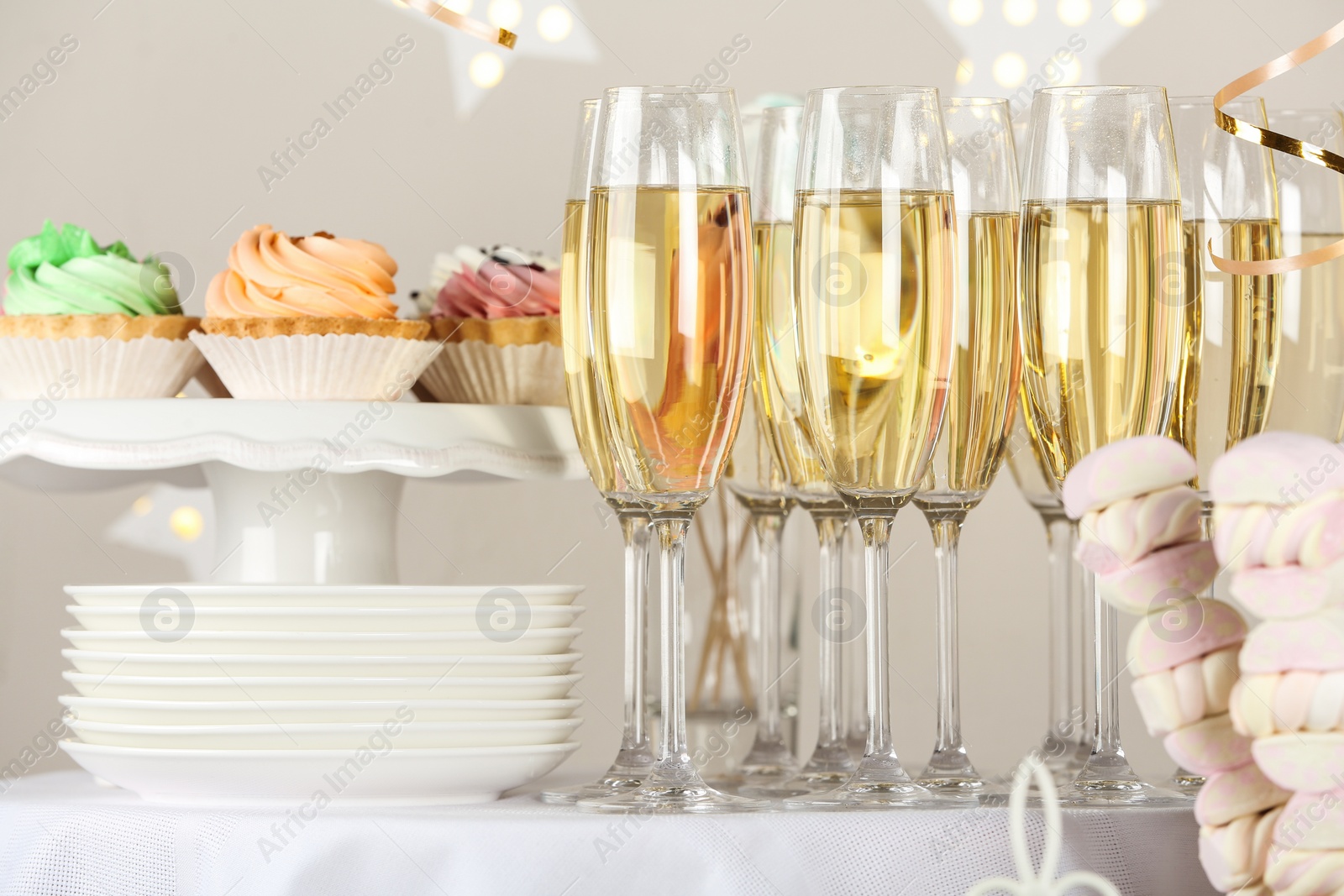 Photo of Candy bar with delicious treats and glasses of champagne for birthday party